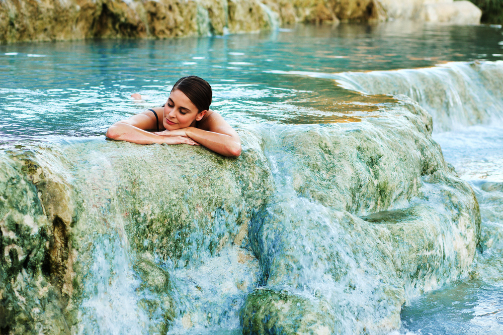 Young-woman-lying-in-the-natural-pool,-Saturnia,-Italy